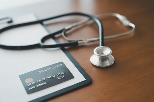 Credit card and stethoscope resting on clipboard in clinical workspace, representing healthcare affordability, patient billing, financial responsibility, and digital payment solutions in medicine.