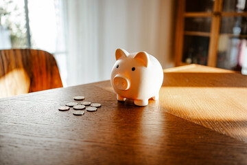 Piggy bank and coins on a wooden table representing savings and financial planning indoors