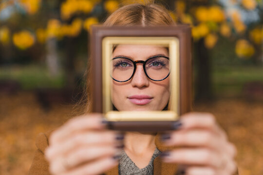 Woman wearing eyeglasses seen through photo frame