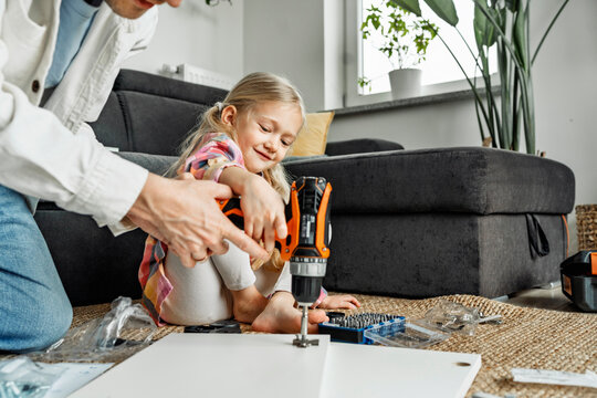 Father and daughter assembling furniture together at home