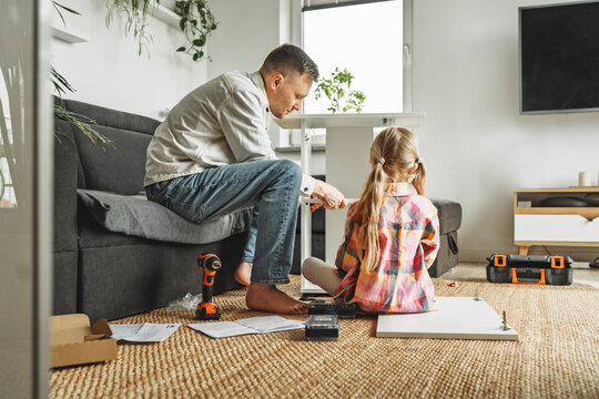 Father and daughter assembling furniture together at home