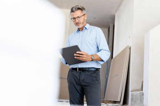 Male professional with eyeglasses using digital tablet at construction site