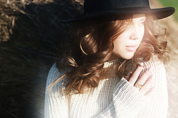 female look in a hat, a model posing in a field of straw