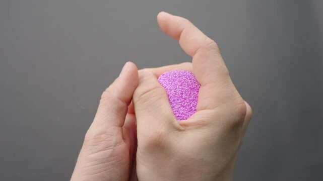 Hands squish and reshape lilac floam slime from a compact cube into an undefined mass, capturing sensory play and deformation on gray background, ASMR session, real time, static camera, close-up shot