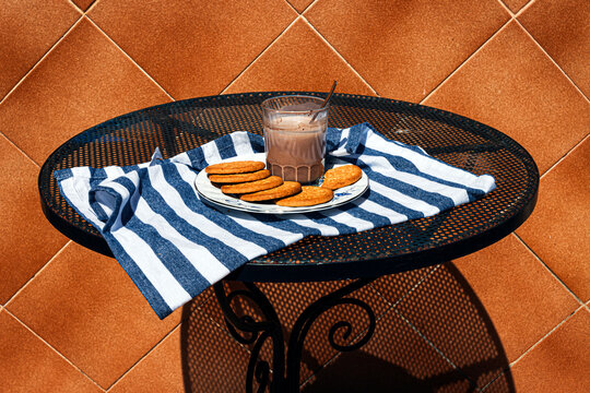 Chocolate milk and biscuits on a metal table outdoors on a summer terrace