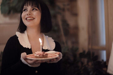 birthday cake with one candle, a girl makes a wish on her birthday