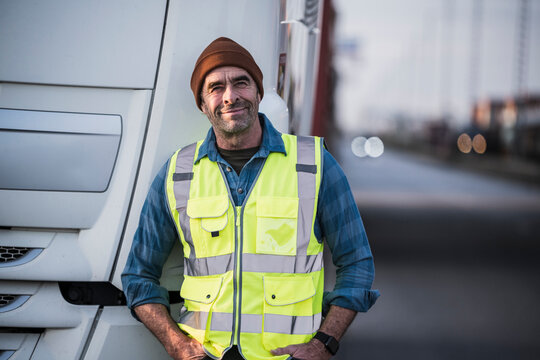 Smiling male truck driver with hands in pockets at industry