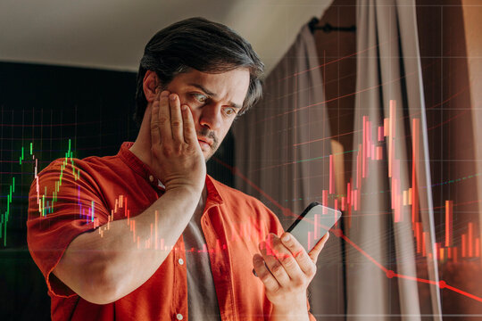 Man in red shirt looking at smartphone with horror as stock market falls