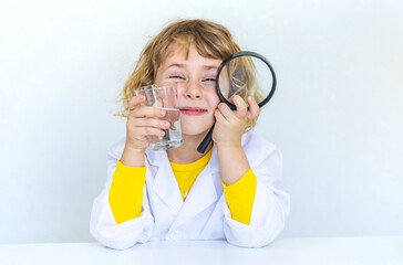A child examines water with a magnifying glass. Selective focus.