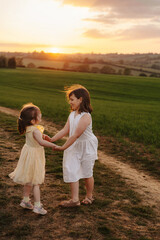 Friends playing and spinning in a green field at sunset.