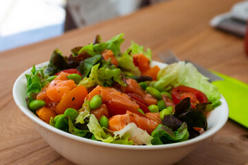 Colorful salmon salad bowl with fresh greens and edamame