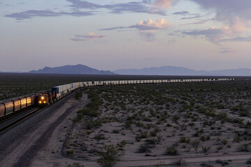 Obraz premium Trains in distance of desert landscape at dusk