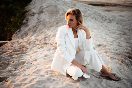 Stunning young woman sitting on sand during photo session