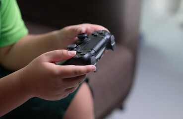 Hands of boy holding gaming consoles at home