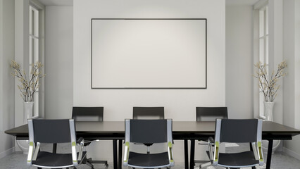 Blank frame or white board or a screen hanging on wall over a long black table and swivel chairs in meeting room