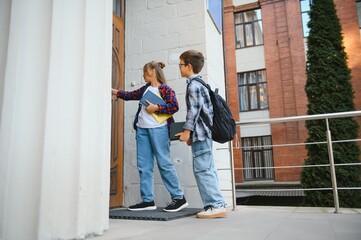 Happy schoolchildren near the school. A boy and a girl are primary school students. School friendship