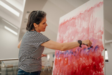 Female artist painting abstract modern art on large canvas in art studio