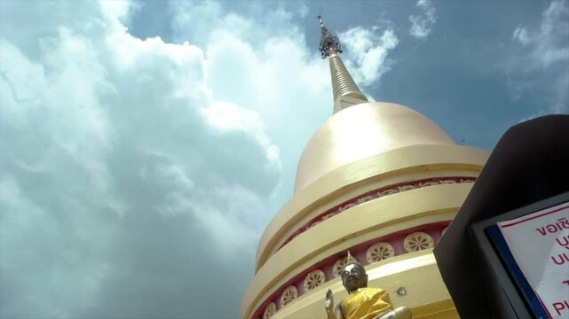 Golden buddhist temple pagoda rising skyward, cloudy background complementing small buddha statue, conveying spiritual tranquility and architectural elegance