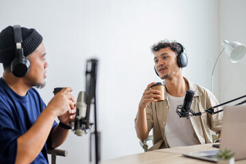 Two Young Content Creators Recording an Internet Podcast While Holding Coffee Cup