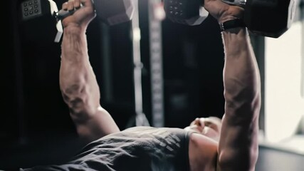 Weightlifter performs dumbbell bench press exercise in a fitness studio - Powered by Adobe