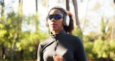 Woman, running and fitness with headphones in forest for spring jog, workout or outdoor exercise. Active, female person or runner with sunglasses for health, cardio or wellness in woods or nature - Powered by Adobe
