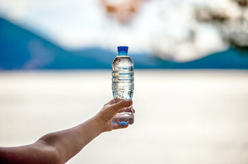 Girl holding a bottle of drinking water at sunset
