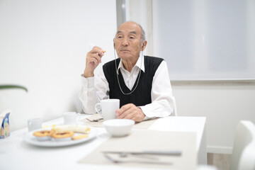 Elderly man enjoying breakfast and contemplating in retirement home