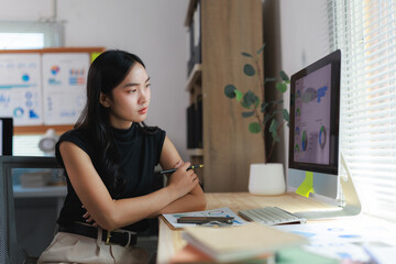 Businesswoman analyzing financial charts on computer in modern office