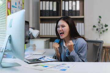 Excited businesswoman celebrating success while working on computer in office