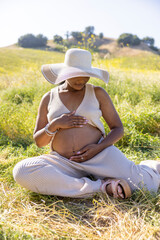 Imagine a serene scene of a pregnant woman relaxing outdoors on a warm summer day, highlighting the elegance of pregnancy amidst a stunning natural backdrop, showcasing the harmony of life and nature