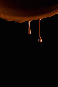 Drops of milk chocolate against black backdrop