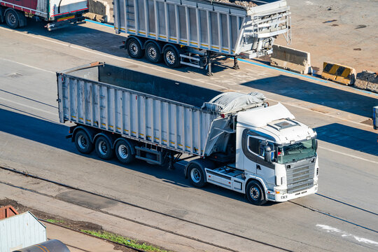 White semi truck with empty tipper trailer on industrial road, photo
