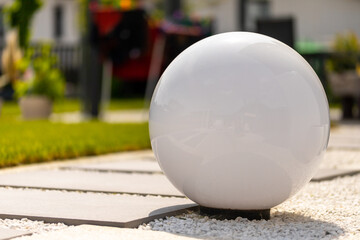 White lamp in spherical shape on a white stone bed with terrace slabs