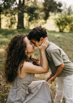 Close-up of mother and son pressing foreheads together in a tender moment in a forest park. Emotional family connection.