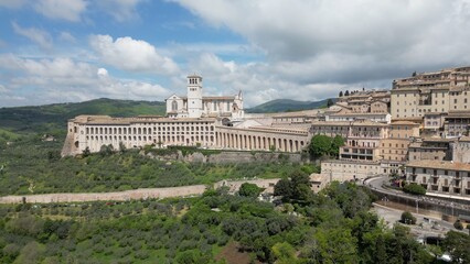 Obraz premium EUROPE, ITALY ASSISI 06,04,2025 The Basilica of Saint Francis San Francesco in Assisi, Umbria.Drone aerial view of Papal Patriarchal Basilica of Saint Francis and the historic city with tiled roofs
