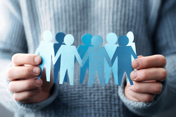 Man holds blue paper figures representing human resources and crowd management in a creative visual concept