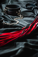 Fototapeta na wymiar Black and red bdsm accessories on dark fabric