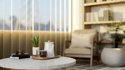 Teapot and a glass cup of iced tea on round marble table in living room or study room with bookshelf