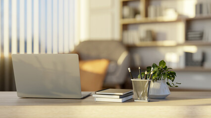 Laptop on wooden table with books and pencils of a living room with large bookshelf or library.