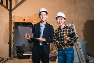 Asian male and female engineers examine construction blueprints and review material costs steel and...