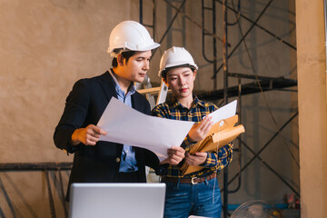 Asian male and female engineers examine construction blueprints and review material costs steel and...