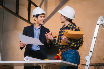 Asian male and female engineers examine construction blueprints and review material costs steel and limestone, preparing competitive bid proposal for building project in collaboration with project