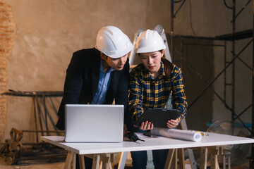 Asian male and female engineers examine construction blueprints and review material costs steel and limestone, preparing competitive bid proposal for building project in collaboration with project
