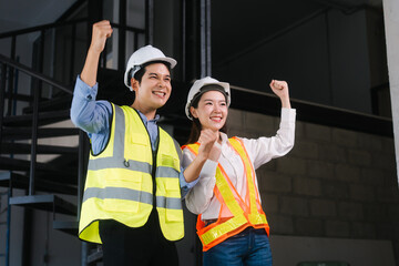 Asian male and female engineers wearing safety vests and helmets inspect structural elements,...