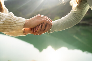 Close-up of two women holding hands in nature, symbol of female friendship, trust, empathy and...