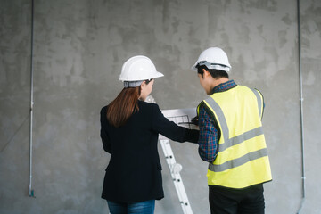 Asian male and female engineers wearing safety vests and helmets inspect structural elements,...