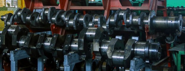 Industrial workshop displays various crankshafts organized in a row for inspection during daytime operations in a manufacturing facility