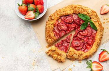 Delicious homemade strawberry galette with almond flakes and fresh mint on baking paper