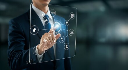 A businessman in a dark suit interacts with a transparent holographic interface displaying various business icons and data visualizations.