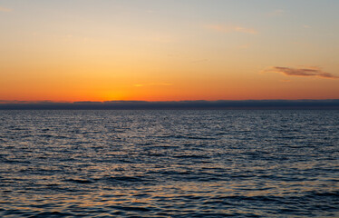 The ocean is calm and the sky is a beautiful orange color